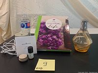 Full lot showing The Essential Life book, Serene House Fan Diffuser with oil and manuals, and Lampe Berger filled with fragrance liquid.