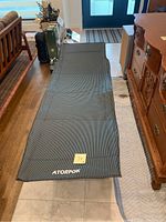 Full view of the unfolded Atorpok folding camping cot with fabric surface showing logo