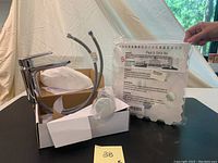 Photo showing Riobel single hole bathroom faucet with attached hoses and pop-up drain assembly, box visible, peel & stick backsplash tile pack held upright.