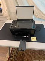 HP Deskjet F4435 multifunction printer with scanner lid open, front paper tray extended, showing device from front angle on table.
