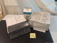 6 sheets of black square tiles, 6 sheets of white penny round tiles, and a box of Permacolour grout on a table