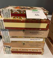 Top view of stacked six cigar boxes showing Partagas and Romeo y Julieta branding and seal labels on edges.