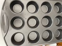 Close-up of a 12-cup muffin baking tin with non-stick gray surface.