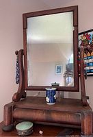 Front view of the redwood framed makeup mirror showing the rectangular mirror glass and the wooden base with drawer closed. Mirror glass shows wear and some missing edging.