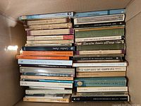 Photo showing a stacked view of several books with visible titles and variety of authors and subjects.