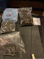 Bags with numerous rectangular and other shaped buckles in bronze finish.