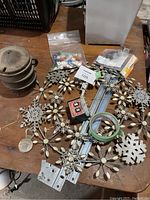 Lot arranged on wooden surface including cast iron pot, metal wreath, bag of dice, power supply, and drawer slides.