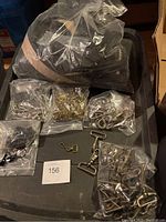 Wide shot of all metal clips, hooks, zipper, and hardware packed in bags and displayed on black tray.