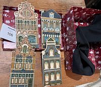 Four ceramic tiles resembling Copenhagen architectural facades shown on wooden surface alongside red and white patterned box.