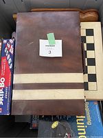 Photo showing multi board wooden game case with cloth wrapped fold and chess/checkers board partially visible