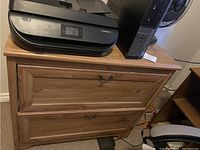 Front view of the Ikea Hemenes pine wood file cabinet with two drawers, showing the natural wood grain and metal handles.