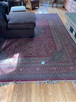 Large red Persian-style rug in living room displaying overall pattern and dimensions
