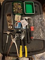 Overview photo of leather working tools including hole punch, riveters, steel rivets, hammers, and grommets