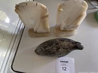 Pair of marble horse head bookends and an Inuit-style soapstone seal carving displayed together on a white surface, showing overall shape and materials.