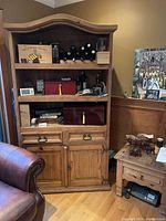 Mexican pine armoire displaying two open shelves with various items on them, two drawers with metal handles, and a two-door cabinet at the bottom.