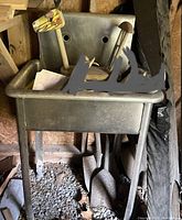 Stainless steel work sink with a vintage wooden horse pull toy inside the sink basin, positioned upright with leg supports visible underneath.