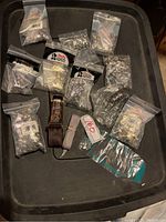 Full view of assortment of leatherworking hardware bags and tools arranged on a black tray.