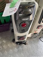 Close up of control panel with red dial and power switches on one heater, showing De'Longhi brand