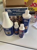 Photo of four bottles of UV3 leather furniture care products arranged in an open box on a white surface.