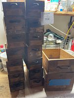 Stack of twelve small wooden drawers shown alongside two larger wooden drawers.
