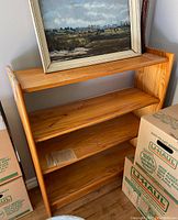Front view of wooden bookshelf showing three shelves and natural wood grain finish.