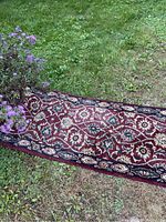Close-up of the runner carpet edge and pattern beside purple flowers to highlight colors and texture.
