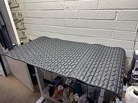 Foam mat spread out on a surface showing full length with pebble textured surface in black color.