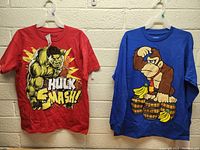 Image of two boys shirts hanging on hangers: a red short-sleeve Hulk Smash shirt and a blue long-sleeve Donkey Kong shirt.
