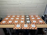 Photo showing 16 packs of Halloween-themed orange napkins with large black polka dots arranged on a table.