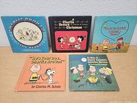 Photo showing five vintage Charlie Brown books arranged in two rows with illustrated Peanuts character covers.