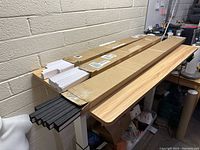 Three cardboard cases containing new paper blinds resting on a wooden table against a beige cinderblock wall.