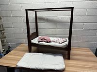 Wooden canopy doll bed with mattress, bedding, and extra pad on white mattress