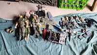 Overview of all items spread out including 5 larger army dolls, smaller action figures, toy jet plane, jeep, and various weapon accessories