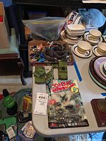 Overview photo showing a table with green tank, helicopter, armored vehicle, assorted toy soldiers and a Combat Mission packaged playset.