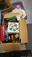 Photo of cardboard box filled with assorted holiday decorations and linens