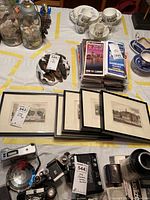 Multiple framed college campus prints laid out on a table along with other assorted items, showing the lot contents.