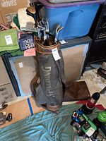 Photo showing the full Spalding golf bag holding various golf clubs, placed on a floor surrounded by boxes and other items.