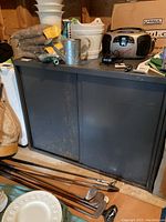 Full front view of dark gray metal cabinet with sliding doors, showing wear and scratches on surface.