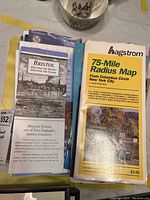 Photo showing a stack of maps and guides including a yellow and white Hagstrom 75-mile radius map of New York City and a Bristol guide booklet.