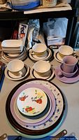 Full overview of all teacups, saucers, stacked plates, and butter dish arranged on table.