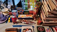 Photo of assorted vintage tin toys including Atomic Robot Man with original box, tin train cars, and various collectible tins. Shows layout of the collection on a table.