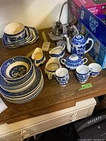 Photo showing entire dishware set including plates, cups, bowls, teapot, creamers arranged on wooden surface