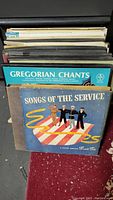 Photo of multiple classical vinyl record album box sets stacked vertically showing a variety of titles with visible front covers including Gregorian Chants and Songs of the Service.