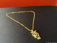 Gold-plated necklace with tiger-shaped pendant decorated with rhinestones, shown fully extended on a flat surface.