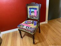 Front view of antique wooden chair with colorful patchwork quilt upholstery on backrest and seat, showing carved backrest top and turned legs with casters.