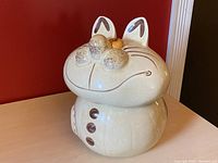 Front right view of vintage Doranne Of California ceramic cat cookie jar showing the wide grin, textured nose, ear details and button front with tail design on side.