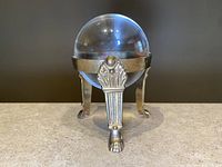 Front view photo showing the glass crystal ball held in the brass base with detailed leg design and claw feet.