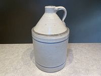 Front view of the stoneware jug showing the body and handle with blue and white banding.