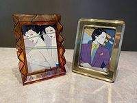 Two mid century photo frames side by side on a gray surface, one amber plastic frame and one brass frame.