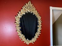 Full front view of the oval mirror against red wall